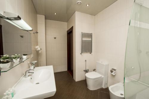 a white bathroom with a sink and a toilet at Passage Hotel in Baku