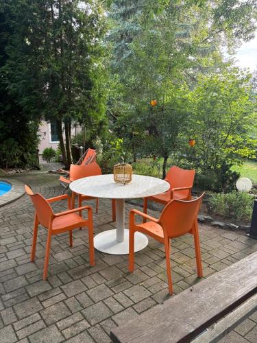 a table and chairs with a white table and orange chairs at Weinberg 100 in Dresden