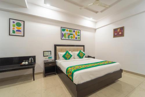 a bedroom with a large bed and a desk at Treebo Shivam Inn Near Singapore Mall in Lucknow