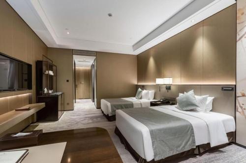 a hotel room with two beds and a flat screen tv at Golden Eagle Summit Hotel Kunshan in Suzhou