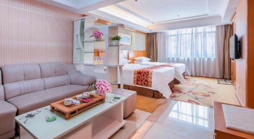 a living room with a couch and a bed in a room at Vienna Hotel Guangzhou Tianhe South China Botanical Garden Metro Station in Guangzhou