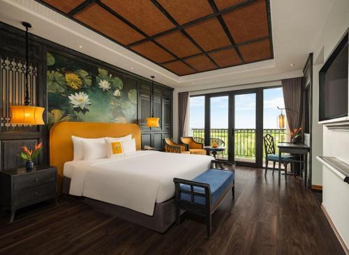 a bedroom with a large white bed and a balcony at Shining Riverside Hoi An Boutique & Spa in Hoi An