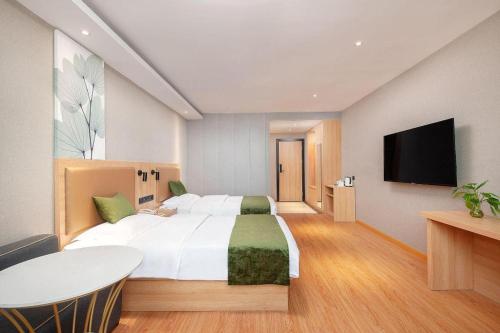 a bedroom with a large bed and a flat screen tv at GreenTree Inn Shanghai Jiading Anting Motor City Express Hotel in Shanghai