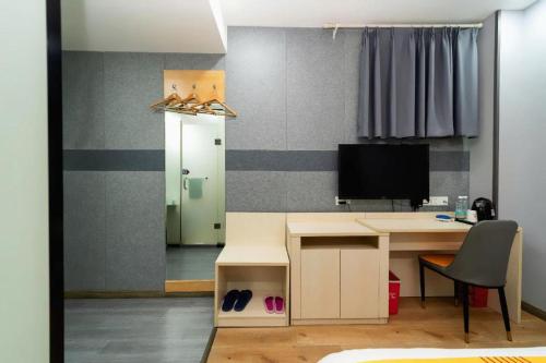 a room with a desk with a television and a chair at Pai Hotel Xi'an Electronic Zheng Street in Xi'an