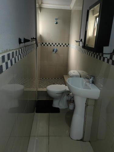 a bathroom with two toilets and a sink and a mirror at Budget Garden House in Durban