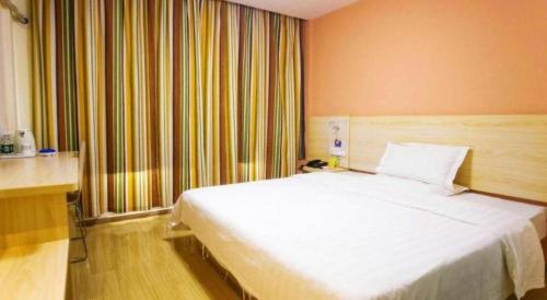 a bedroom with a large white bed in a room at 7 Days Inn Yiyang Shengli Road in Shangrao