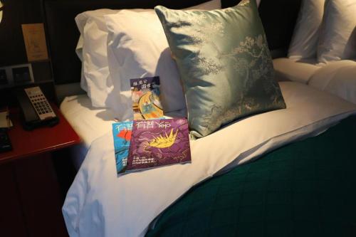 a bed with two books and pillows on it at Ethos Hotel Wuhan Riverside in Wuhan