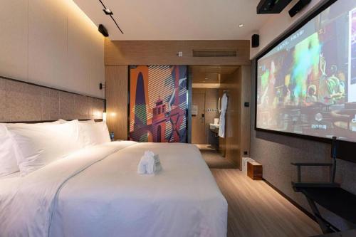 a hotel room with a large bed and a flat screen tv at Ethos Hotel Wuhan Riverside in Wuhan