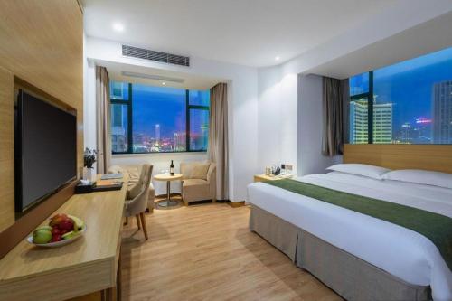 a hotel room with a large bed and a television at GreenTree Inn Zhongshan West District Fuhua Road Branch in Zhongshan