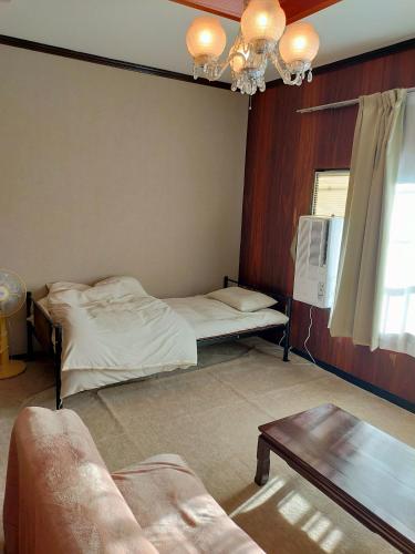 a room with a bed and a couch and a table at 民泊いなほ館 in Shiso