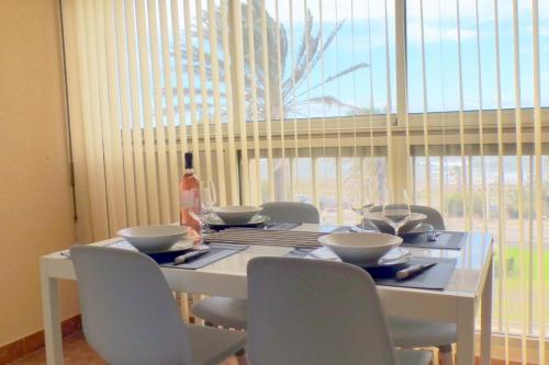 einen Esstisch mit Stühlen und eine Flasche Wein in der Unterkunft Comfortable apartment with pool facing the sea in Six-Fours-les-Plages