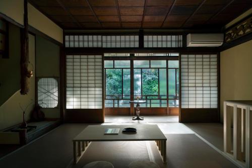 a room with a table in a room with windows at UTAHI  A 100-years-old Kyoto machiya in Kyoto