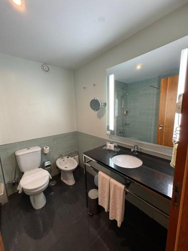 un bagno con due lavandini, un water e uno specchio di Hotel Vila Galé Cerro Alagoa ad Albufeira