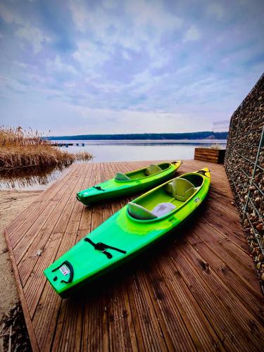 two green kayaks sitting on a wooden dock at Apartament Premium View w Riva Zegrze, Jezioro Zegrzyńskie in Zegrze Południowe