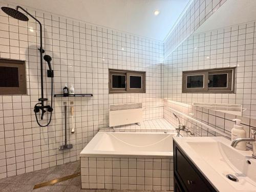 a white tiled bathroom with a tub and a sink at Terrace Rooftop Luggage Storage Spacious Two Rooms Beam Projector 4 Beds Jeonpo Seomyeon Busan Station in Busan