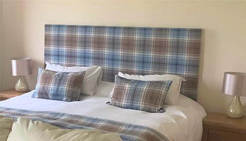 a bed with two pillows and a plaid head board at Merkister Hotel in Harray