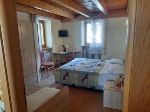 a bedroom with a bed and a table and a desk at AlpinaBnB in Castello Tesino