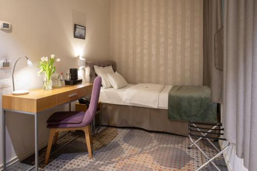 a bedroom with a bed and a desk with a purple chair at Jump INN Hotel Belgrade in Belgrade