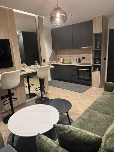 a living room with a couch and tables and a kitchen at Apartments Lana in Mostar