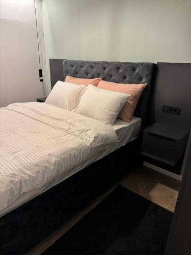 a bed with white sheets and pink pillows at Apartments Lana in Mostar