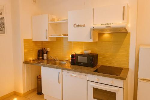 Una pequeña cocina con fregadero y microondas. en Appartement 4 voyageurs avec terrasse et WIFI - Proche Cité Médiévale, en Carcassonne