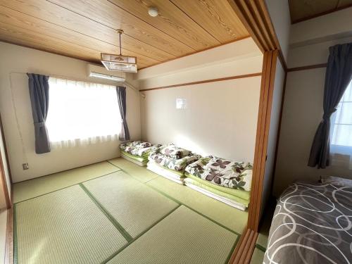 a room with three beds in a room with a window at Ueda Building - Vacation STAY 8562 in Asahikawa