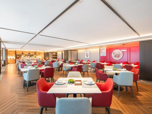 a restaurant with white tables and red chairs at Guiyang Airport Outlets Yicheng Hotel 