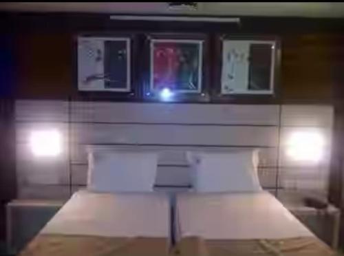 a bed with two pillows and a wall with lights at HoTEL TANIYA in Vijayawāda