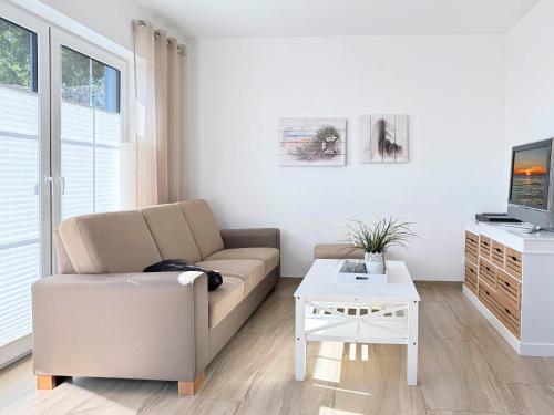Una sala de estar con un sofá y un televisor. en Strandhafer, en Zingst