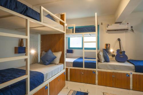 a room with two bunk beds and a guitar at Shalom Backpackers Anjuna Goa in Anjuna