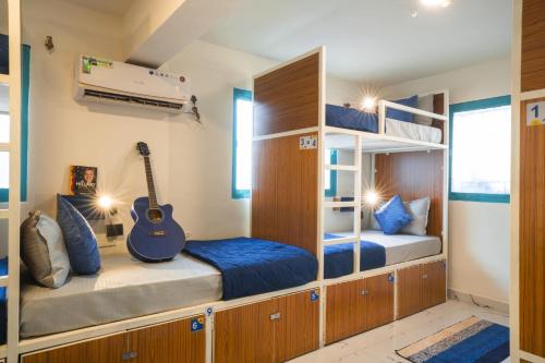 a bunk bed room with two beds and a guitar at Shalom Backpackers Anjuna Goa in Anjuna