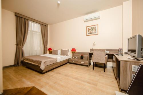 a bedroom with a bed and a desk and a television at Passage Hotel in Baku