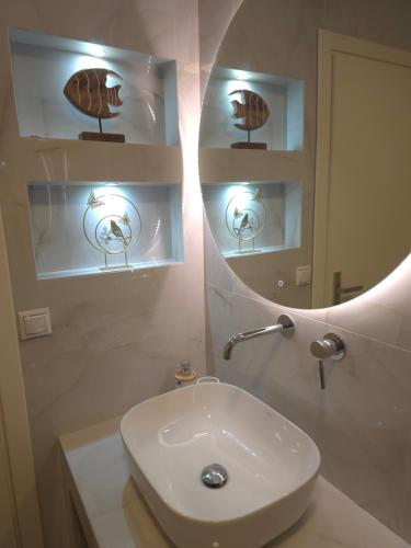 Preveza Lux & Comfort Suites في بريفيزا: حمام أبيض مع حوض ومرآة