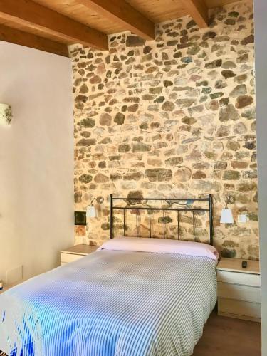 a bed in a room with a stone wall at La casa del Río in Pujayo