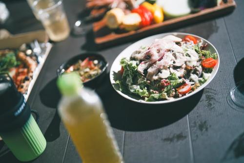 a table with a bowl of salad and a bottle of juice at HANABI棟-BASE棟 サウナ BBQ 農業体験 花火 が楽しめる ペット可 貸し切りで最大12名宿泊可能 Wi-Fi完備 in Katori