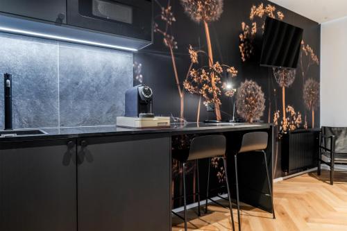 a kitchen with black cabinets and a counter with stools at Hotel Skjern in Skjern