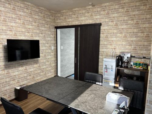 a room with a table and a tv and a brick wall at penthouse半田 in Handa