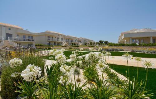 a garden with white flowers in front of condos at Cozy Apartment In Marzamemi With Wifi in Marzamemi