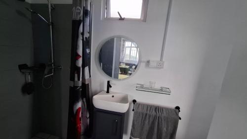a white bathroom with a sink and a mirror at Résidence La Montagne Studio in Tambe