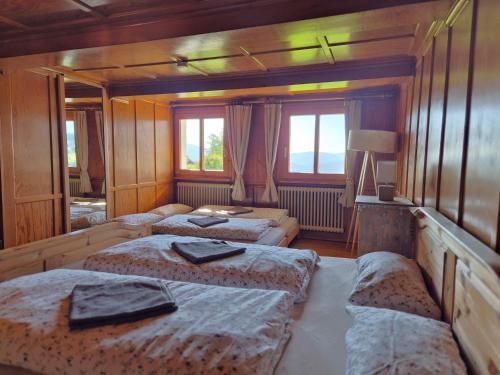 a bedroom with three beds in a room with windows at Echtes Schwarzwaldhaus - Traditionell & Modern in Bernau im Schwarzwald