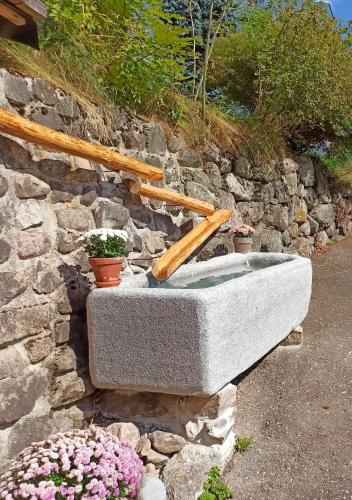 a stone bath tub sitting next to a stone wall at Echtes Schwarzwaldhaus - Traditionell & Modern in Bernau im Schwarzwald