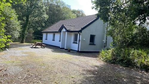 a white building with a picnic table in front of it at Ardnagashel Estate No 4 in Ballylickey