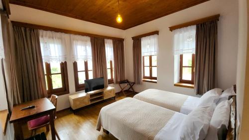 a bedroom with a bed and a desk and windows at Bizant House Boutique Hotel in Gjirokastër