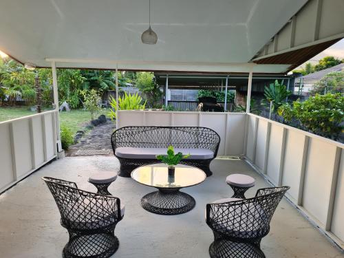 a patio with chairs and a table and a couch at Taharu'u Guest House By The Beach in Papara