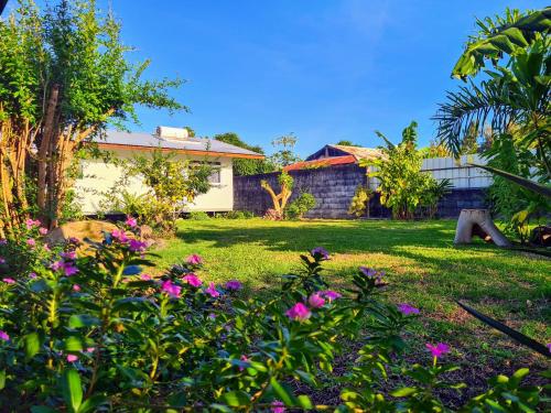 a yard with pink flowers and a house at Taharu'u Guest House By The Beach in Papara