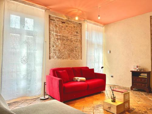 a red couch in a room with a brick wall at baroLOFT in Barolo