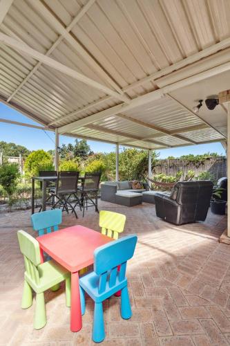 a patio with a table and chairs under a roof at Family Escape Walk To Beach Park Views in Mandurah