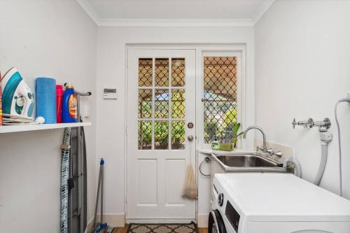 a small kitchen with a sink and a door at Family Escape Walk To Beach Park Views in Mandurah