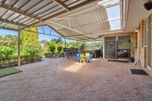 an outdoor patio with awning and tables and chairs at Family Escape Walk To Beach Park Views in Mandurah