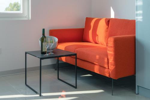 an orange couch and a table with a bottle of wine at TQ City Apartments in Radanovići